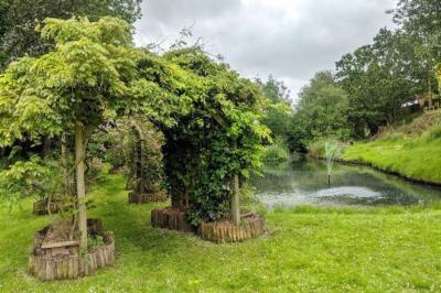 garden with a tree arch and pond with a water fountain in it